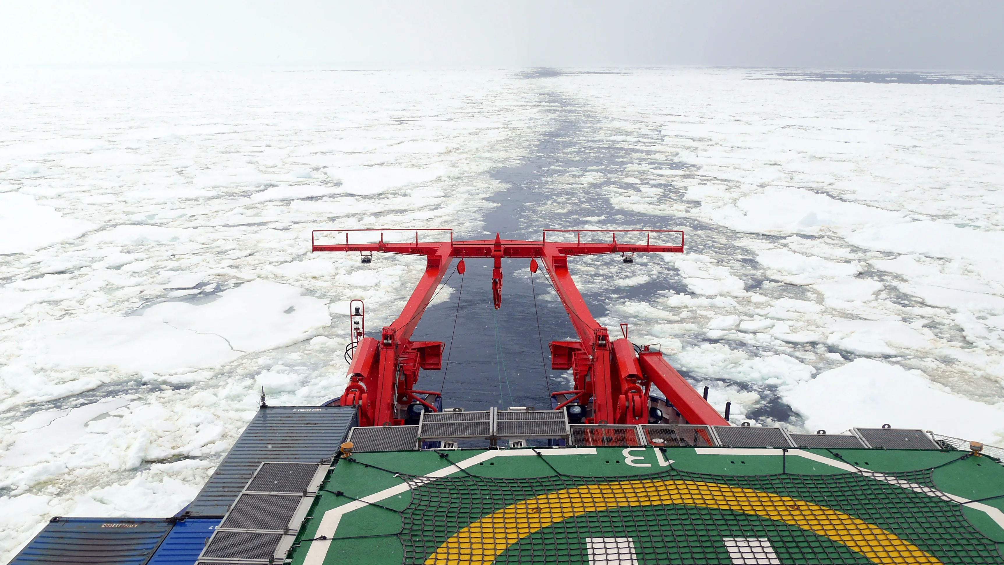 A line of clear water through sea ice, viewed from the stern of the ship, just visible.