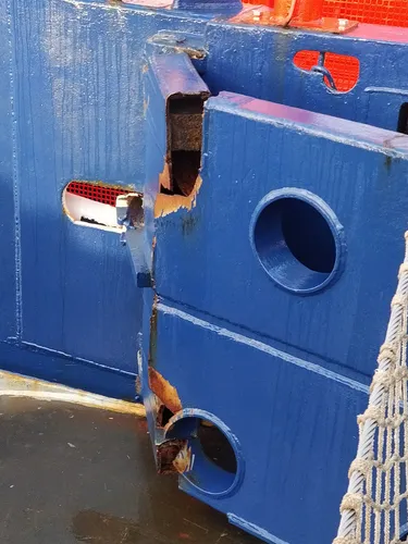 A heavy steel block forming a gate, with a rusty tear near the hinges